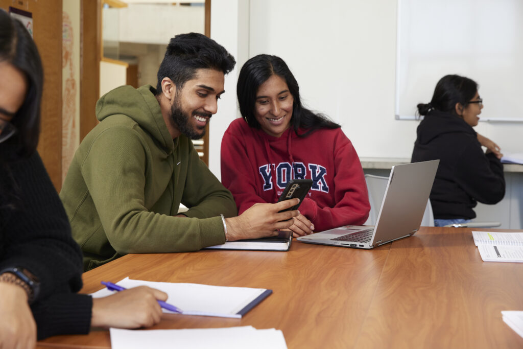 two students smiling in front of a laptop