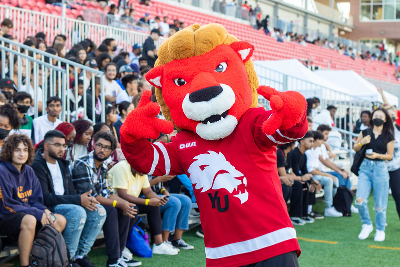 Yeo the Lion mascot posing in front of crowds of students at York Orientation.