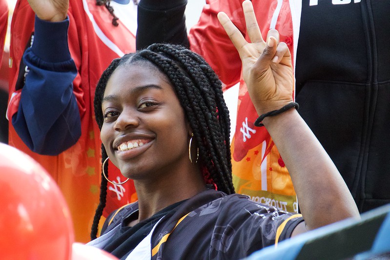 Close up of a student giving a peace sign to the camera in the midst of a crowd of other students.
