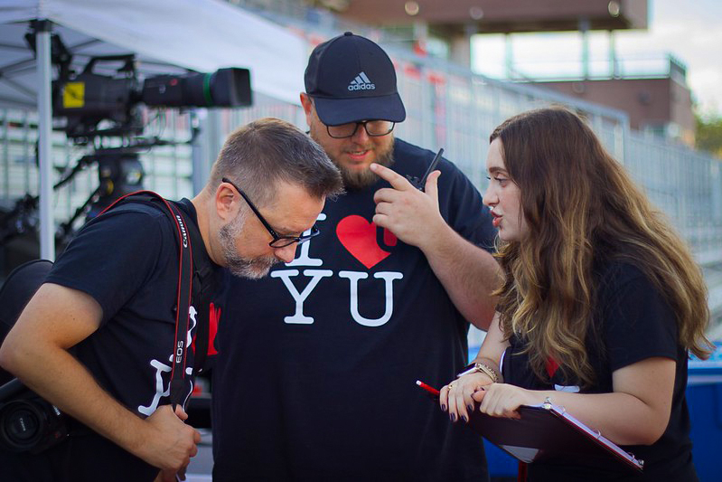 Three York staff members in black "I Heart YU" t-shirts puzzle over a problem at an orientation event.