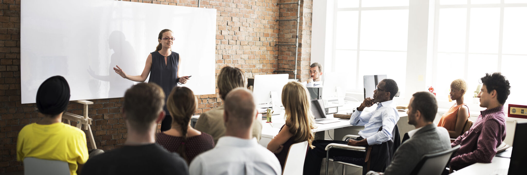 A lecturer teaching in a classroom full of students.