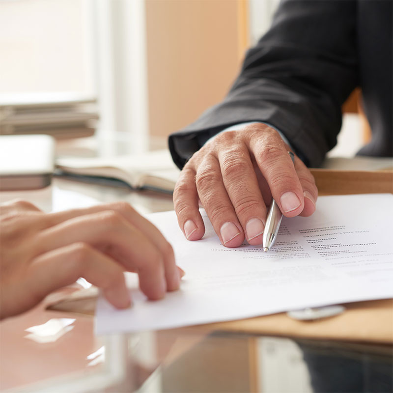 Close-up of a hand with a pen resting on a document.