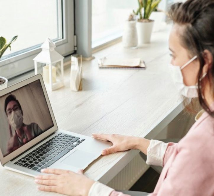 Two people wearing masks video calling on laptop 