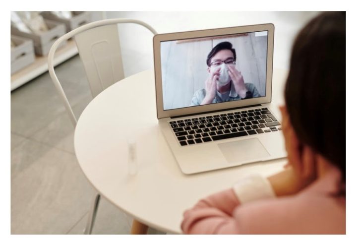 A person in a meeting with another person who is wearing a mask