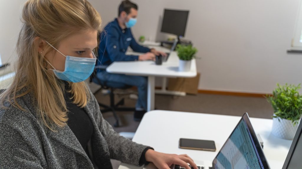 Two people sitting in front of laptop with mask.