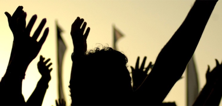 A silhouette of people raising their arms in the air. 