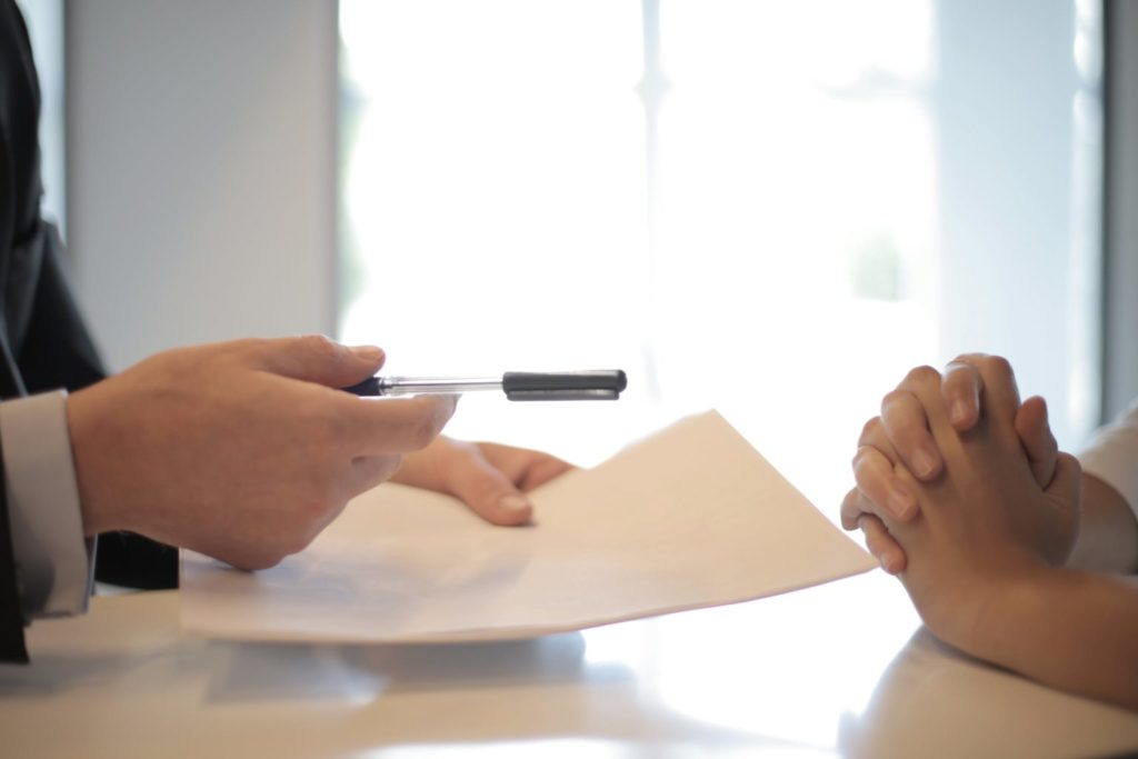 Two sets of hands, one holding a pen and paper