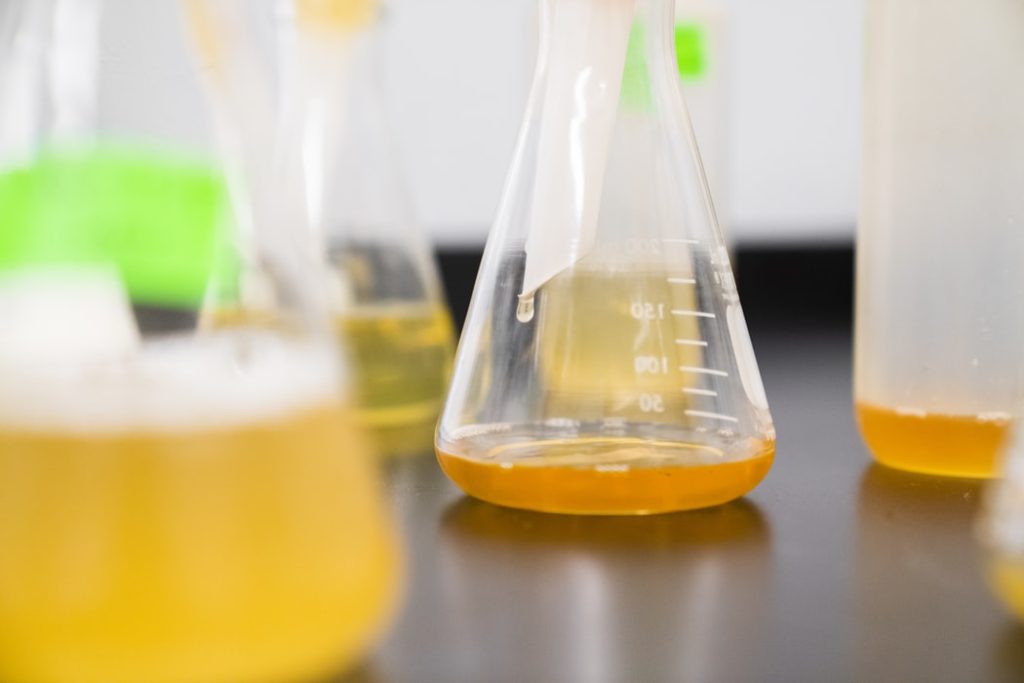 Bottle in Chemistry lab on table with yellow liquid.