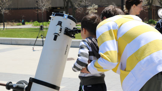 Child looking through a telescope