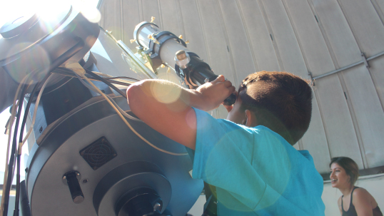 Child looking through a telescope