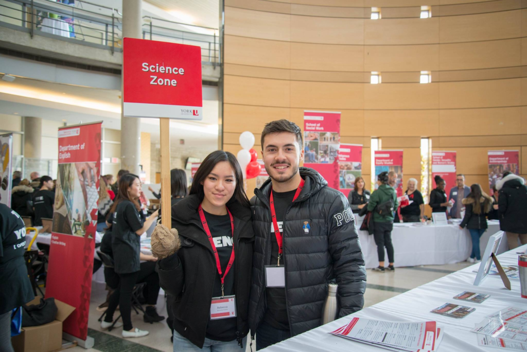 Two students holding a Science Zone sign at an event on campus.