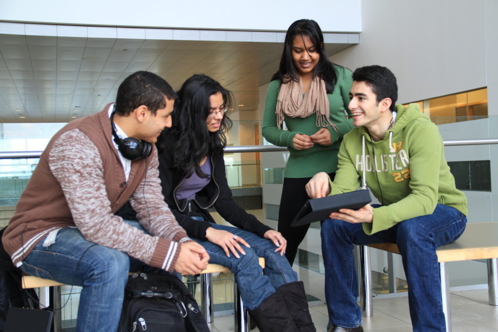 Four students sitting and talking on campus.