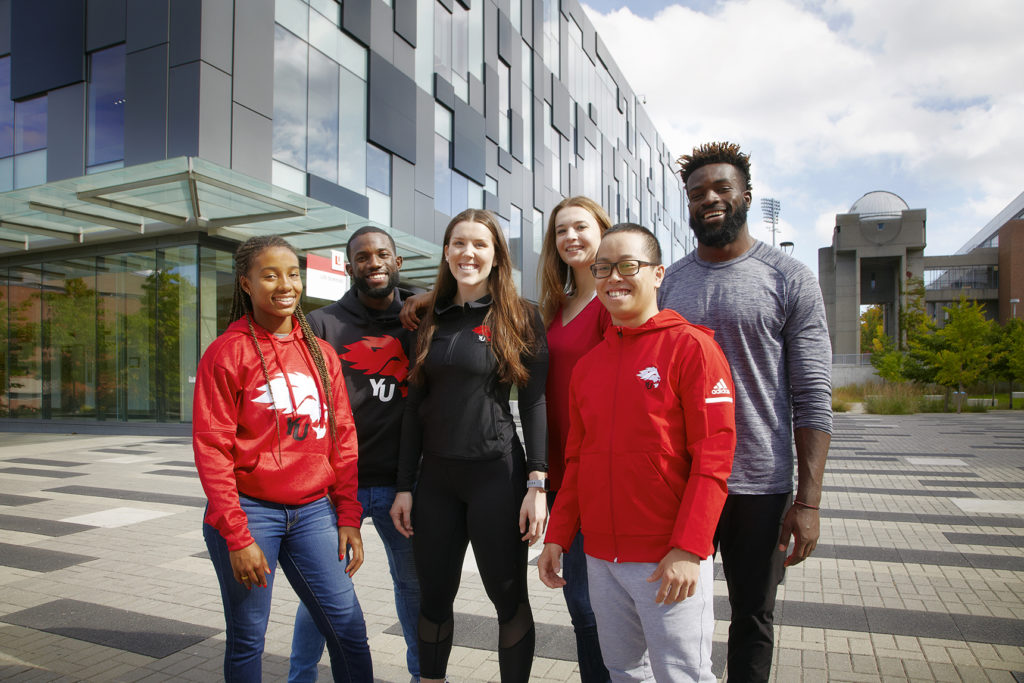 Six students standing outside in front of a building. 