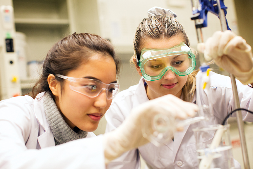 Two students wearing safety googles in a science lab