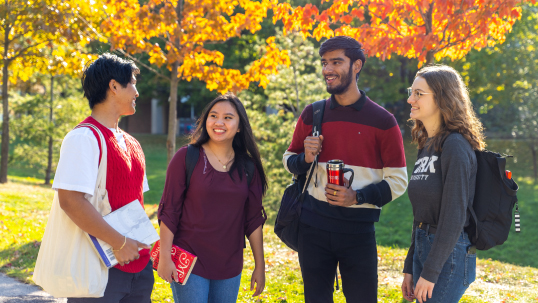 Four students standing outside laughing