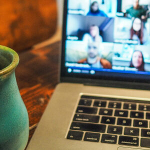 Image of a zoom meeting on a laptop next to a coffee mug