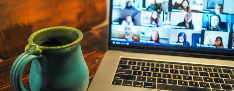 Image of a zoom meeting on a laptop next to a coffee mug