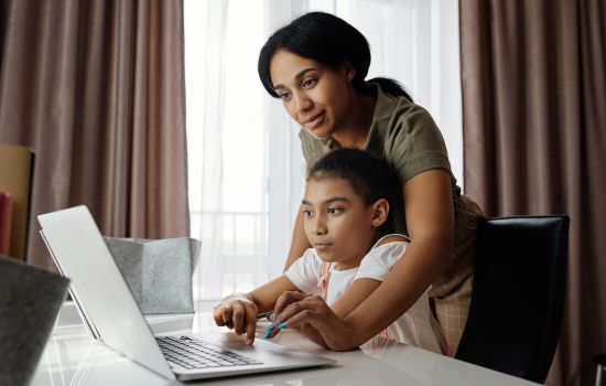 A mother and daughter looking at a computer monitor
