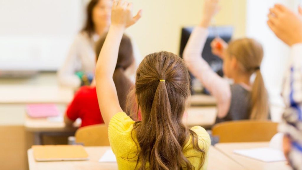 A young girl raising her hand in a classroom
