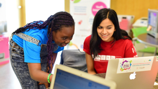 An instructor and student looking at a laptop