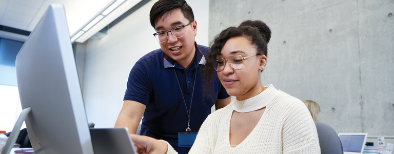 Two students work together on a computer.