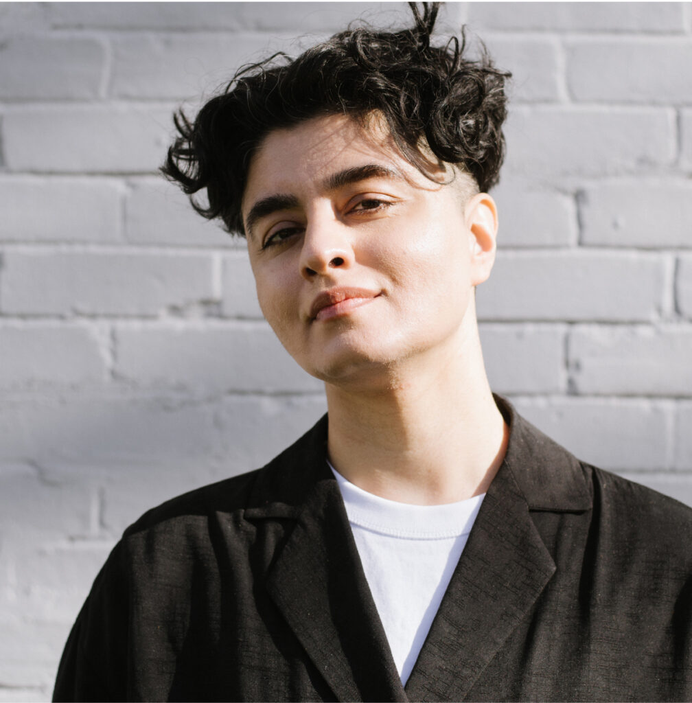 Portrait photo of Samra Habib against a white, brick wall.