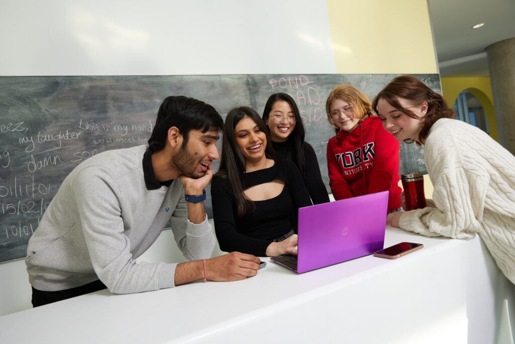 Group of students looking at a computer. 
