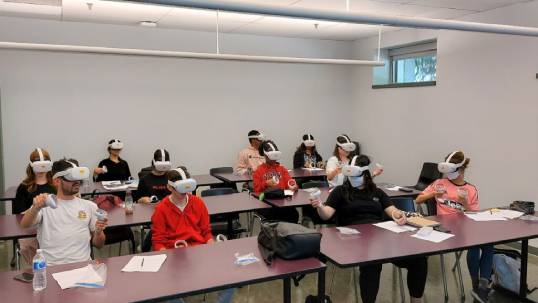 A classroom of students using virtual reality headsets.