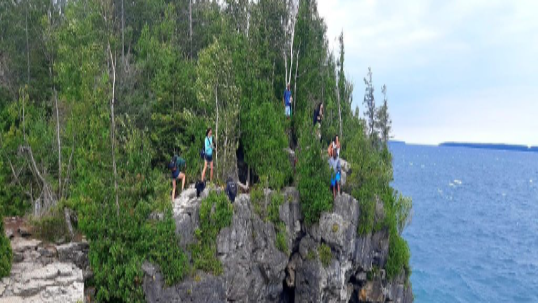 The Grotto in Bruce Peninsula featuring  trees and students standing on a cliff.
