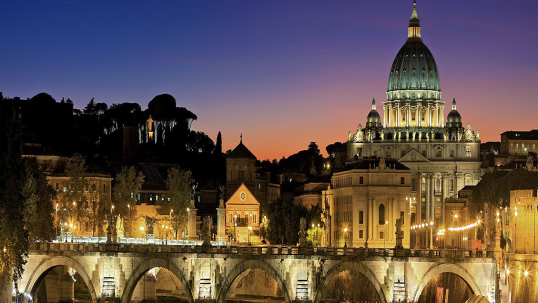 Italy at night with lit-up bridge and buildings.