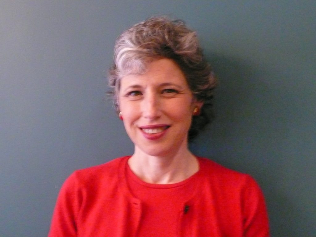Marlene Bucholtz smiling at the camera, standing in front of a grey background
