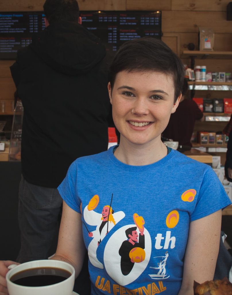 Morgan Anderson, a doctoral candidate with short brown hair who is wearing a blue t-shirt, smiling into the camera