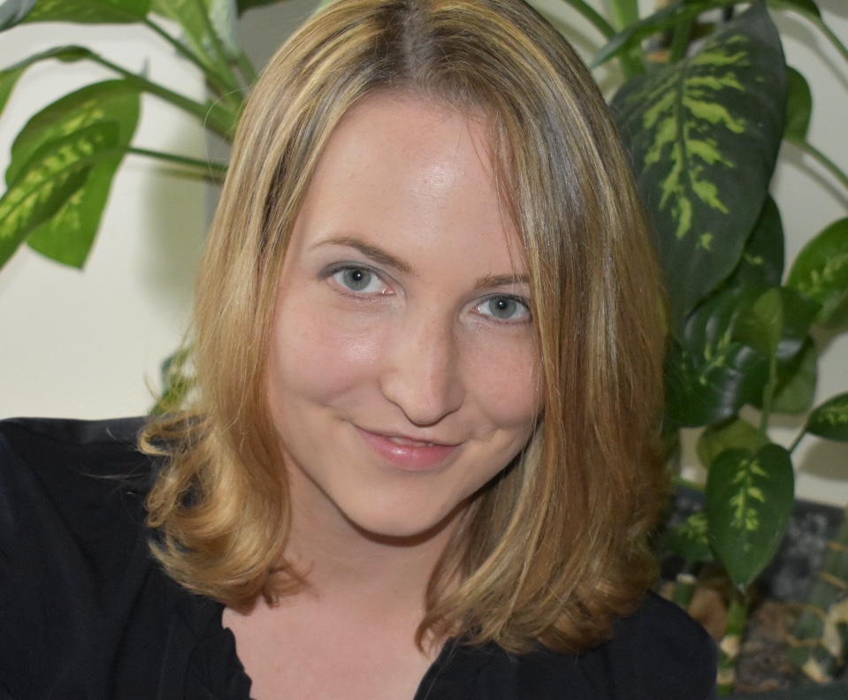 Dr. Katharina Pabst, a blonde individual with shoulder-length hair, wearing a blue blouse, smiling into the camera.