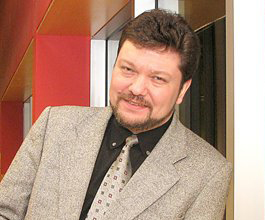 Robert Winkler, an individual with short brown hair and a beard, wearing a light grey suit, smiling into the camera.