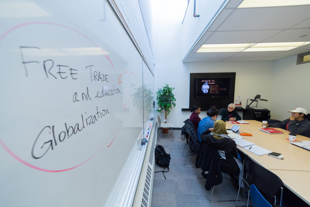 A group sitting in a classroom with the words "free trade and globalization" written on the whiteboard