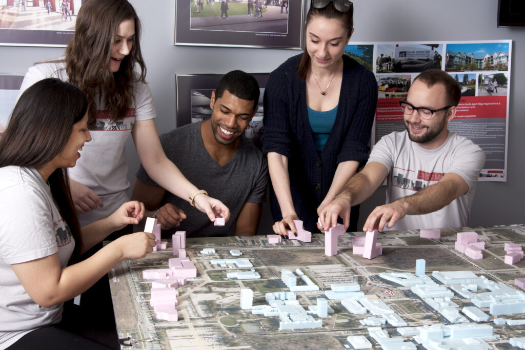 A group of diverse individuals gathered around a map with manipulatives, collaboratively designing together