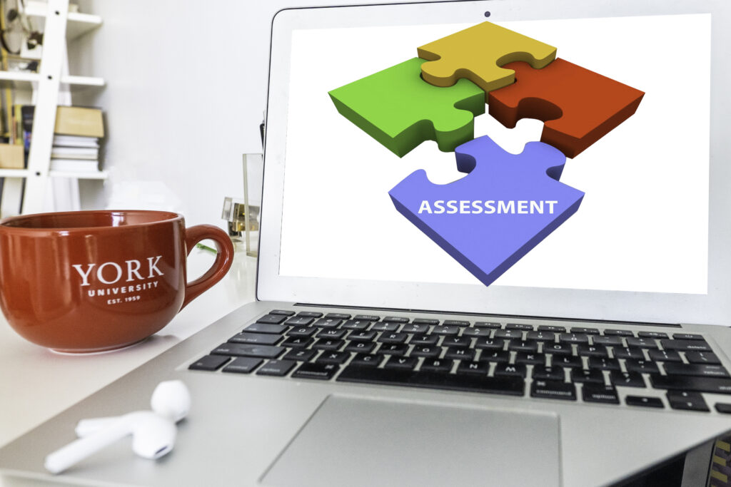 this is a decorative image that show assessment and puzzle pieces on the screen of a laptop with a red coffee cup and the York University logo on it
