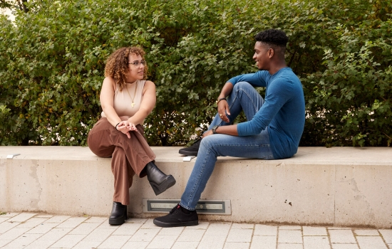 Two YorkU students seated outside having a conversation.