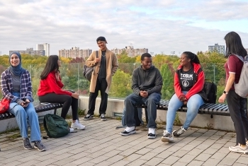 Eight YorkU students standing and sitting atop Bergeron terrace at YorkU.