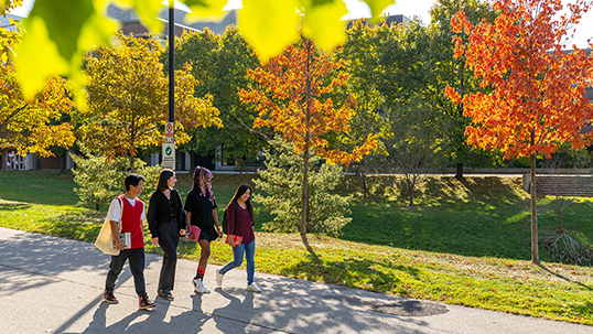 Students walk by campus buildings in Fall