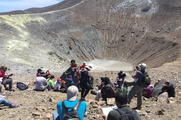 Researches sit beside a large crater