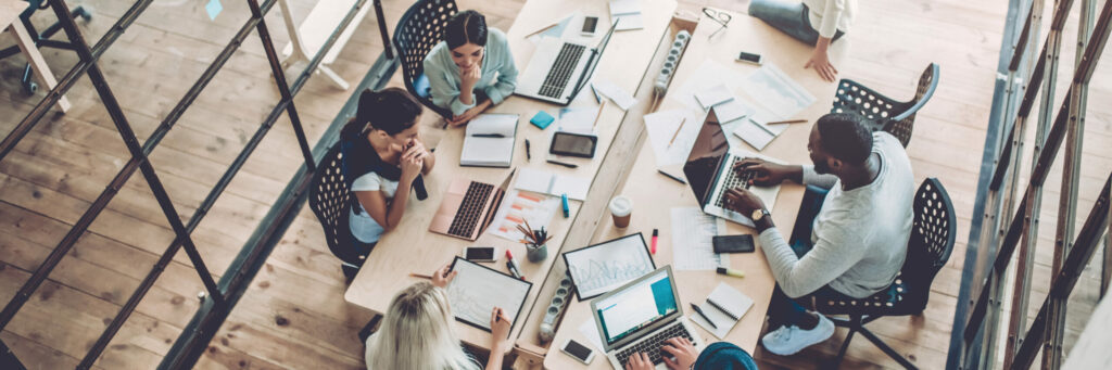 Multiracial young creative people in modern office. Group of young business people are working together with laptop, tablet, smart phone, notebook. Successful hipster team in coworking.