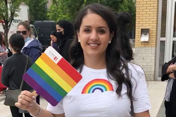 Person holding pride flag and wearing rainbow shirt