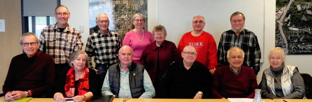 Image of 12 members of the YURA Executive Committee sitting and standing behind a board room table