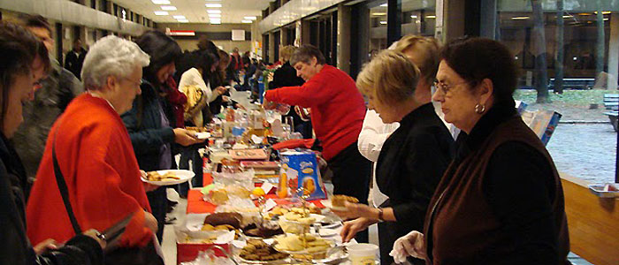 Image of the Showcase "bake table" with several volunteer staff and several shoppers