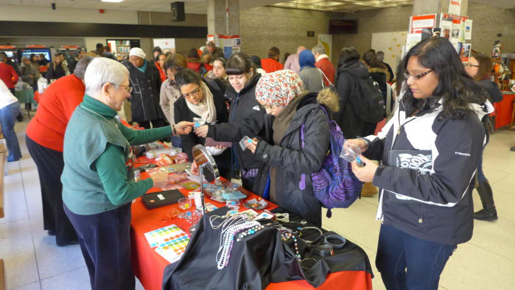 Image of five jewellery shoppers at the Showcase "attic treasures" table, staffed by YURA volunteers
