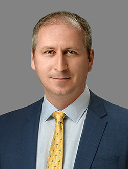 Head & shoulders photo of Dr. Irvin Studin, dressed in a blue suit with a yellow tie